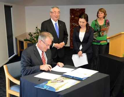 Whakatāne Mayor Tony Bonne , left, and Shibukawa Mayor Sadaji Akutsu, standing, signing the Friendship Agreement at the Whakatāne Civic Centre.