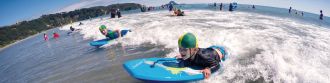Kids boogie boarding at Ohope Beach